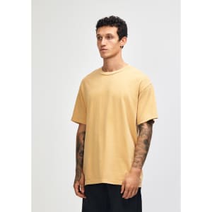 A unisex heavyweight cotton t-shirt in a mustard yellow shade, featuring a relaxed fit and short sleeves.