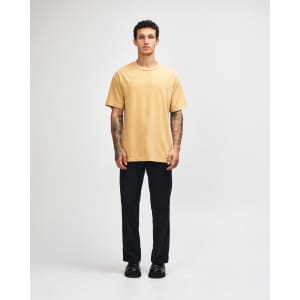 A unisex heavyweight cotton t-shirt in mustard yellow, paired with light blue cargo trousers.