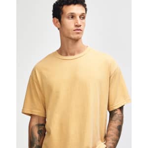A unisex garment dyed heavyweight cotton t-shirt in a soft mustard colour, featuring a relaxed fit and a logo.
