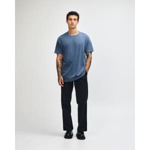 A navy unisex t-shirt made of heavyweight cotton, modelled by a person wearing light cargo jeans.