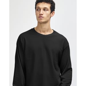 A heavyweight cotton unisex long sleeve t-shirt in black, featuring a logo, displayed on a model.