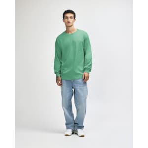 A unisex long sleeve t-shirt in a light aqua colour, paired with loose-fit blue jeans and black sneakers.