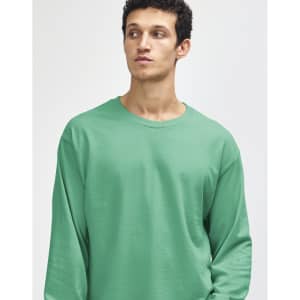 A turquoise heavyweight cotton unisex long sleeve T-shirt on a model, featuring a logo on the sleeve.