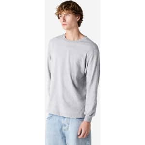 A grey heavyweight cotton unisex long sleeve T-shirt with a casual fit. The model is standing in a relaxed pose.
