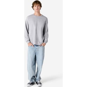 A grey heavyweight cotton unisex long sleeve T-shirt paired with light blue baggy jeans and black shoes.