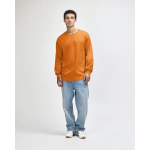 An orange heavyweight cotton unisex long sleeve t-shirt paired with blue jeans, worn by a model.