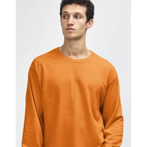 An orange heavyweight cotton unisex long sleeve t-shirt displayed on a model. The shirt has a simple design and logo.
