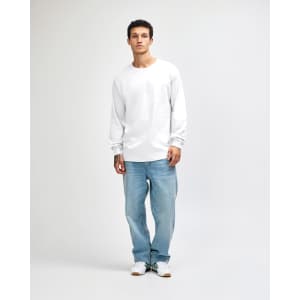 A model wearing a white heavyweight cotton unisex long sleeve T-shirt paired with blue jeans and white shoes.