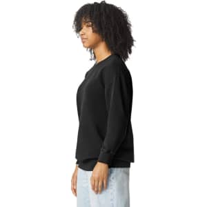 A black crewneck sweatshirt in a side view, featuring a relaxed fit and a logo on the sleeve.