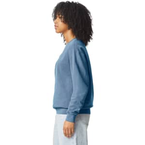A lightweight crewneck sweatshirt in blue, featuring a logo, worn by a person with curly hair.