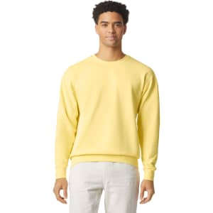 A lightweight crewneck sweatshirt in a bright yellow colour, worn by a model with curly hair. It has a logo on it.