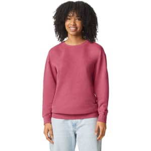 A woman is wearing a lightweight crewneck sweatshirt in a deep maroon colour. The sweatshirt has a logo.