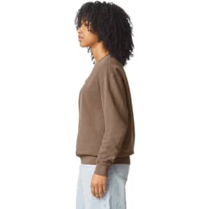 A brown crewneck sweatshirt with a relaxed fit, featuring a side view of a model. It has a logo on the sleeve.