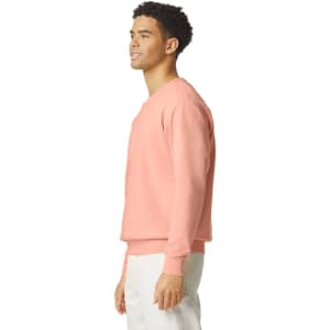 A lightweight crewneck sweatshirt in a soft coral colour, featuring a simple design and a logo.