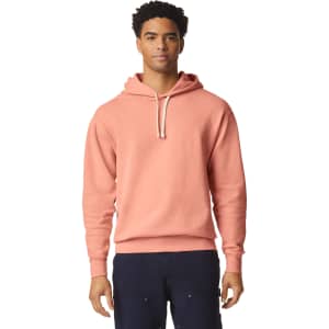A lightweight hooded sweatshirt in a soft coral colour, featuring a drawstring hood and a logo.