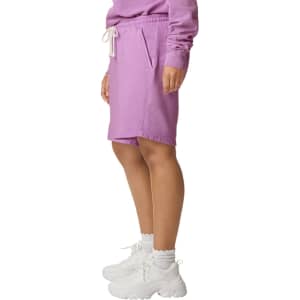 Lightweight sweatshorts in pastel purple, featuring an elastic waistband and side pockets, paired with white footwear.