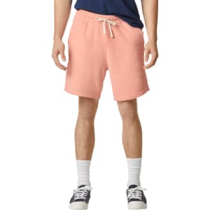Lightweight sweatshorts in a coral hue with an elastic waistband and drawstring, featuring a logo on the side.