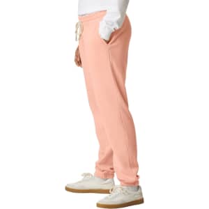 Lightweight peach sweatpants with pockets, featuring an elastic waistband and cuffs, alongside a logo.