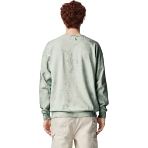 A crewneck sweatshirt in a soft green shade, featuring a textured design and a logo on the back.