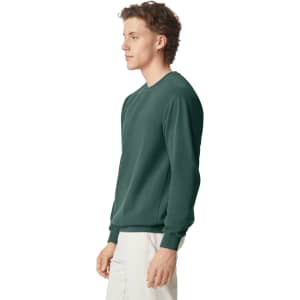 A green adult crewneck sweatshirt is displayed on a model from a side view. It features a simple design and has a logo.