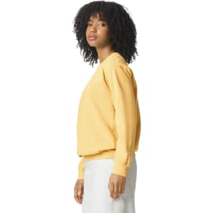 A side view of a woman wearing a yellow adult crewneck sweatshirt. The sweatshirt has long sleeves and a relaxed fit.