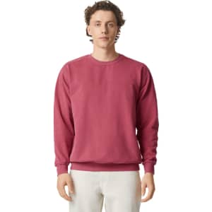A crewneck sweatshirt in a deep pink colour, featuring a relaxed fit and long sleeves. It has a logo on it.