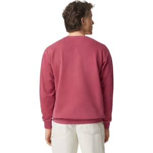 A crewneck sweatshirt in a deep pink shade, featuring a simple design and ribbed cuffs at the wrists.
