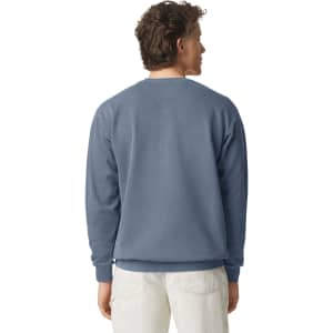 A crewneck sweatshirt in a muted blue colour, featuring a simple design and a logo on the back.
