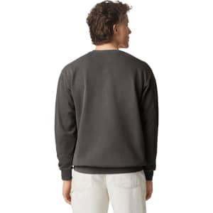 A back view of a grey adult crewneck sweatshirt featuring a logo on the neck. The model is wearing light-coloured pants.