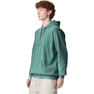 A teal adult hooded sweatshirt with a front pocket and a drawstring hood displayed on a model.