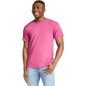 A heavyweight adult t-shirt in vibrant pink, displayed on a smiling male model. The t-shirt has a logo.