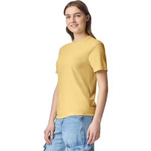 A yellow adult heavyweight T-shirt displayed on a model, featuring a logo. The model is wearing casual denim shorts.