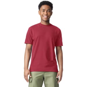 A red adult heavyweight t-shirt displayed on a smiling young model wearing olive green pants. The shirt features a logo.