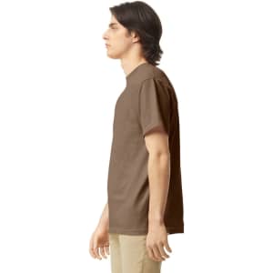 A brown adult heavyweight t-shirt displayed on a model in profile. The shirt has a simple design and features a logo.