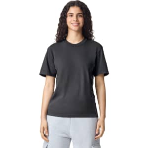 A black adult heavyweight T-shirt displayed on a smiling individual, featuring a round neckline and short sleeves.