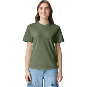 A woman wears an olive green adult heavyweight t-shirt with a casual fit. The shirt features a logo on the front.