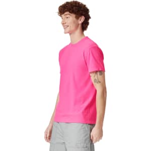 A vibrant pink heavyweight t-shirt displayed on a smiling model, featuring a simple design and a logo.