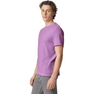 A purple heavyweight t-shirt displayed on a model, featuring a round neckline and short sleeves. The shirt has a logo.