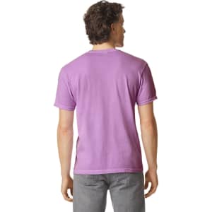 A man wearing a purple heavyweight t-shirt, viewed from the back, with grey pants. The shirt has a logo on it.