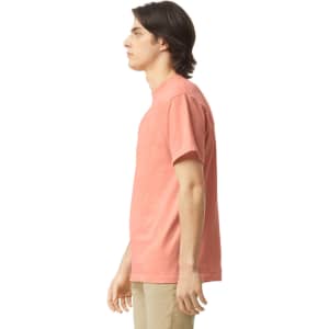 A side view of an adult heavyweight t-shirt in coral colour, featuring a simple design and a logo.