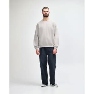 A grey Gildan Heavy Blend adult crewneck sweatshirt worn by a model, paired with black jeans and sneakers.