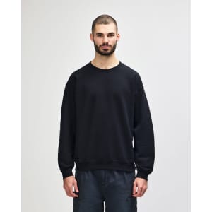 A black Gildan Heavy Blend adult crewneck sweatshirt displayed on a model wearing blue jeans.