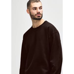 A brown Gildan Heavy Blend adult crewneck sweatshirt displayed on a model, featuring a simple design and a logo.