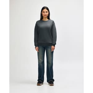 A grey Gildan Heavy Blend adult crewneck sweatshirt worn by a model, paired with black jeans and sneakers.