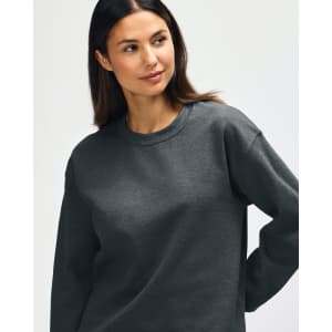 A model wearing a grey Gildan Heavy Blend Adult Crewneck Sweatshirt with long sleeves and a relaxed fit.