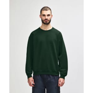 A green Gildan Heavy Blend adult crewneck sweatshirt on a model, featuring a plain design and long sleeves.