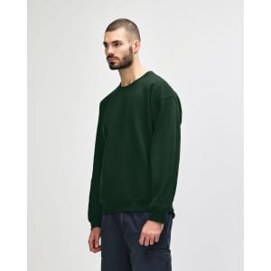 A model wearing a dark green Gildan Heavy Blend Adult Crewneck Sweatshirt, featuring a logo on the sleeve.