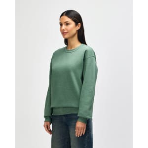 A green crewneck sweatshirt on a model, featuring long sleeves and a relaxed fit. The product has a logo.
