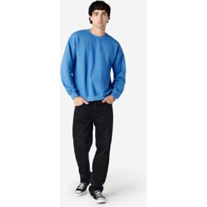 A blue Gildan Heavy Blend adult crewneck sweatshirt paired with black jeans and sneakers, featuring a logo.