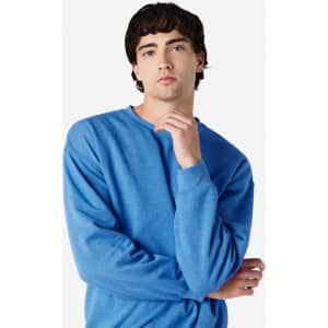 A blue Gildan Heavy Blend adult crewneck sweatshirt with a model posing in a casual setting. The sweatshirt has a logo.